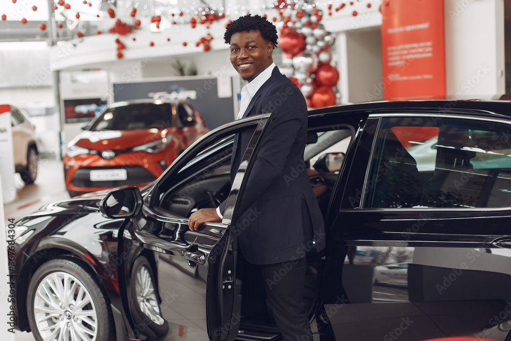 Man buying the car. Businessman in a car salon. Black male in a suit. Man buying the car. Businessman in a car salon. Black male in a suit.