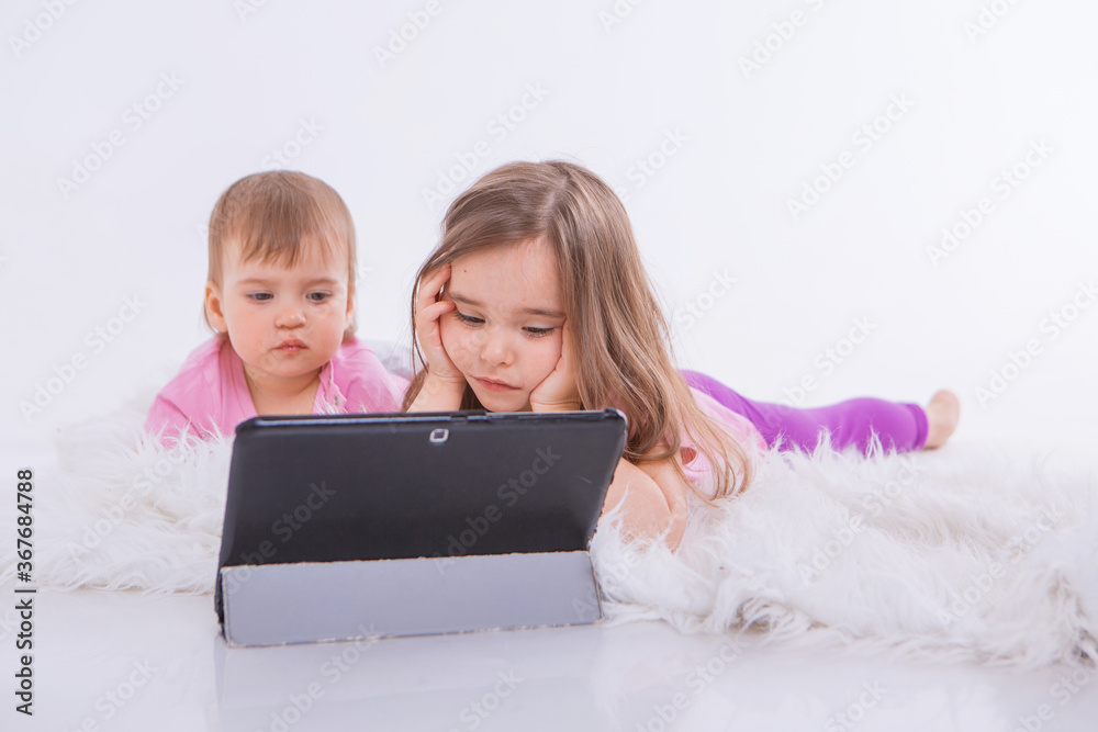 the kids are watching cartoons on the tablet. Home schooling for girls during quarantine the kids are watching cartoons on the tablet. Home schooling for girls during quarantine