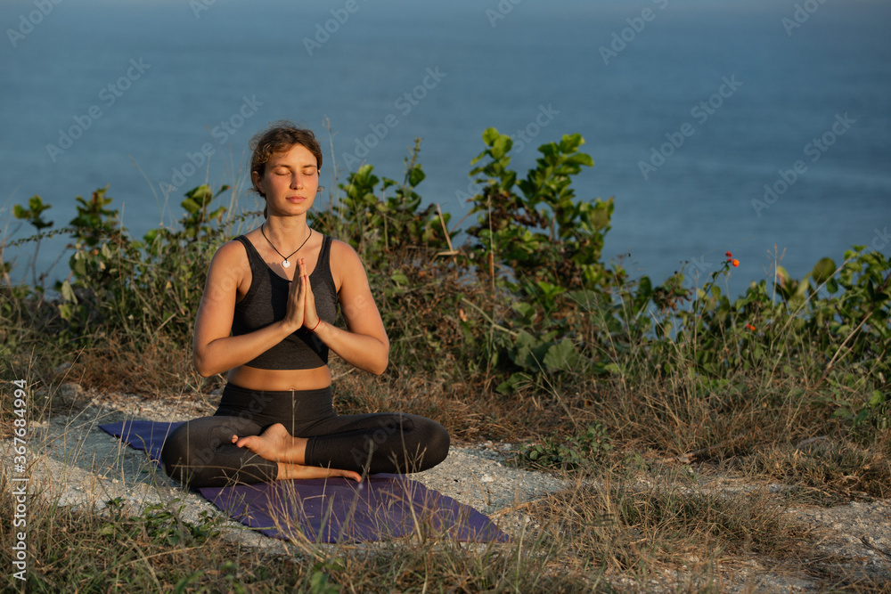 Fototapeta premium Young woman doing yoga outdoors with amazing back view. Bali. Indonesia.