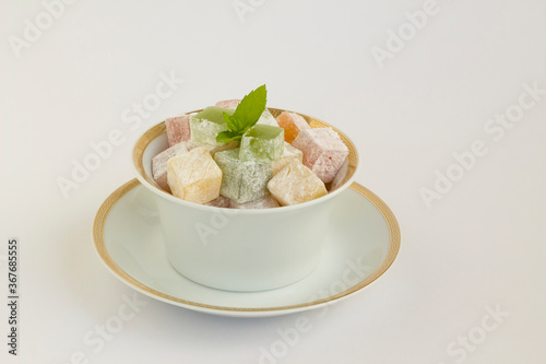 Traditional Turkish Delight on white background with fresh mint and copy space.The Sugar Festival.