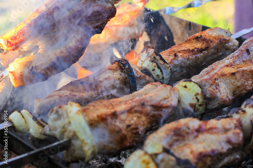 Barbecue skewers with juicy meat cooking in open air in summer. Food background.