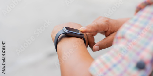close up mature woman hand touch screen on digital smart watch to checking time or health checkup application at home for senior people and lifestyle concept