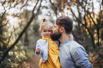 young, stylish bearded father walking with his little daughter in nature at sunset. Family photos of father and one child. selective focus, noise effect