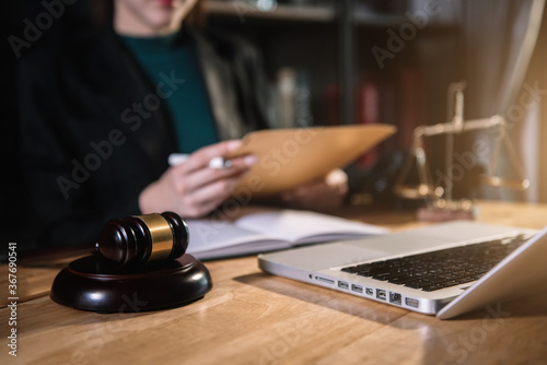 Justice and law concept. Female judge in a courtroom the gavel, working with document and digital tablet computer on wood table.