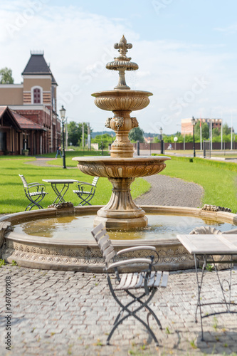 Outdoor cafe terrace with fountain. Empty chairs in cafe or restaurant on summer day. Restaurant terrace in small European city