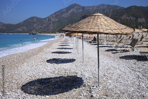 Fototapeta Naklejka Na Ścianę i Meble -  Wooden umbrellas and their shade, on the chic Oludeniz beach in Turkey.