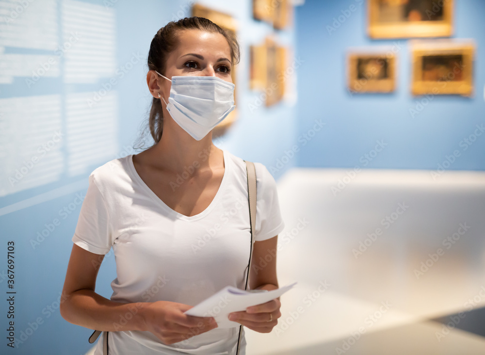 Young woman wearing face mask observing artworks in museum, new normal due to coronavirus outbreak - obrazy, fototapety, plakaty 