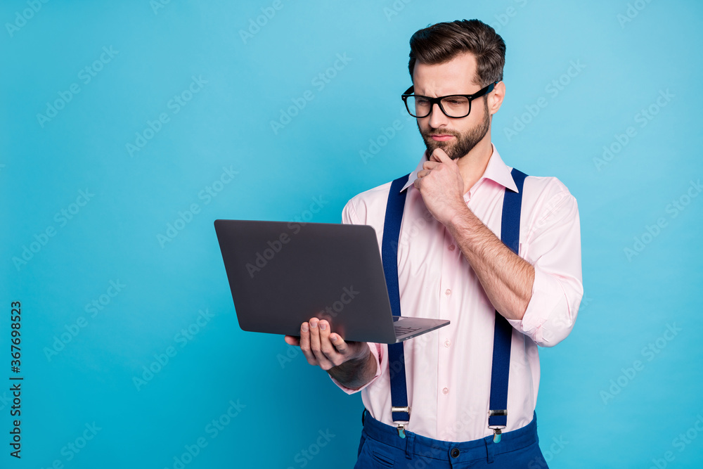 Photo of handsome business man trend outfit guy use eyesight specs working computer read report seriously stay home wear pink shirt suspenders pants isolated blue color background Photo of handsome business man trend outfit guy use eyesight specs working computer read report seriously stay home wear pink shirt suspenders pants isolated blue color background
