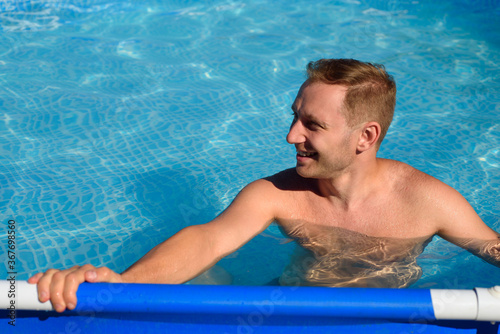 Smilling man is resting in the pool. Isolated summer rest during the coronavirus period. Cottagecore © penyushkin
