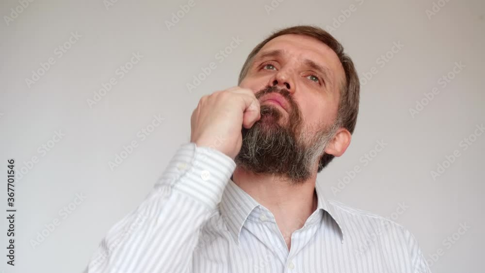 Old man with negligent neard and hair brushes hair. Mature man in white shirt tries to look stylish. Old man with negligent neard and hair brushes hair. Mature man in white shirt tries to look stylish.