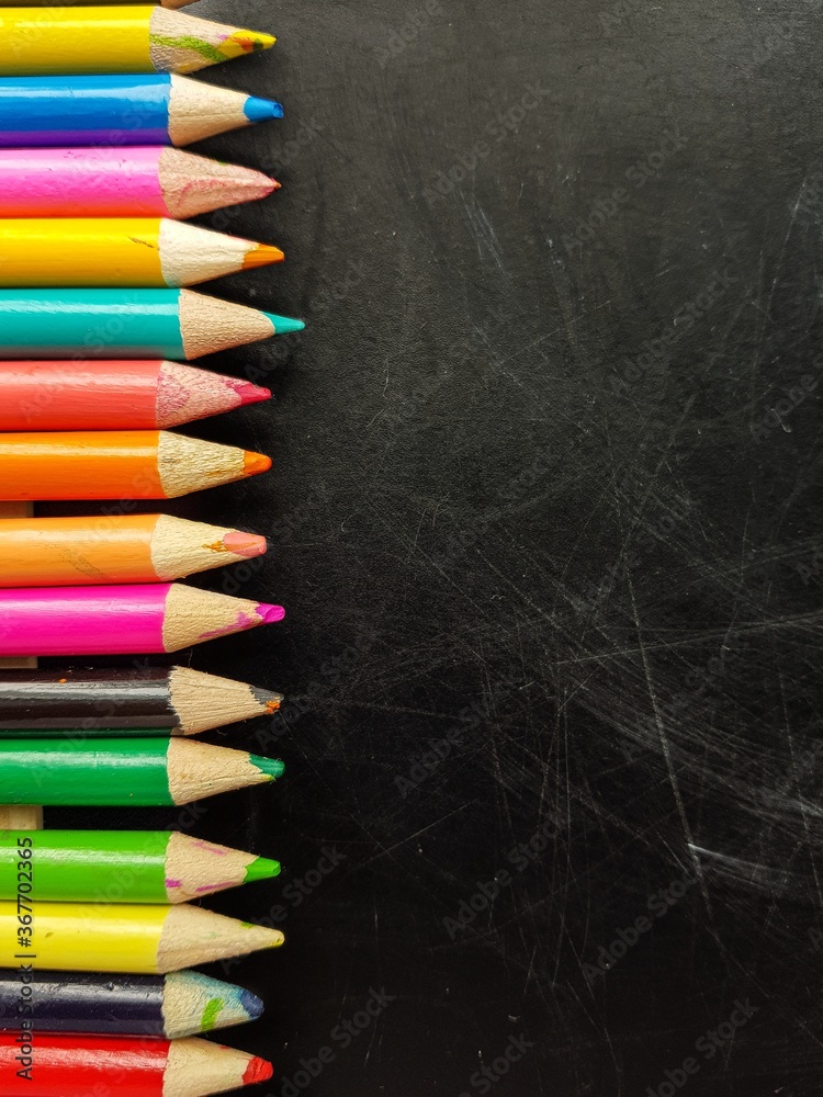 Colored pencils on a black chalkboard. Back to school. Colored pencils on a black chalkboard. Back to school.