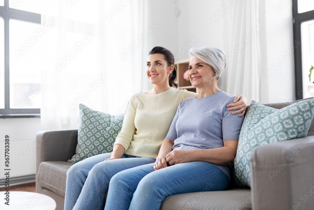 family, generation and people concept - happy smiling senior mother with adult daughter hugging at home