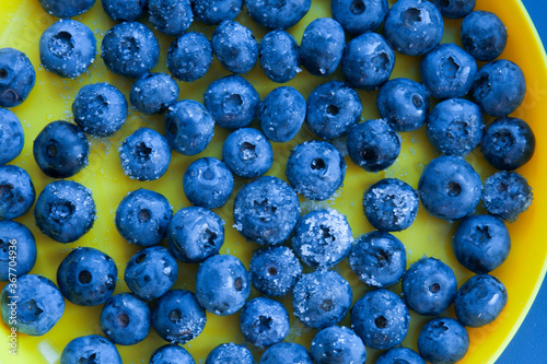 Blueberries with sugar on a background of a yellow plate
