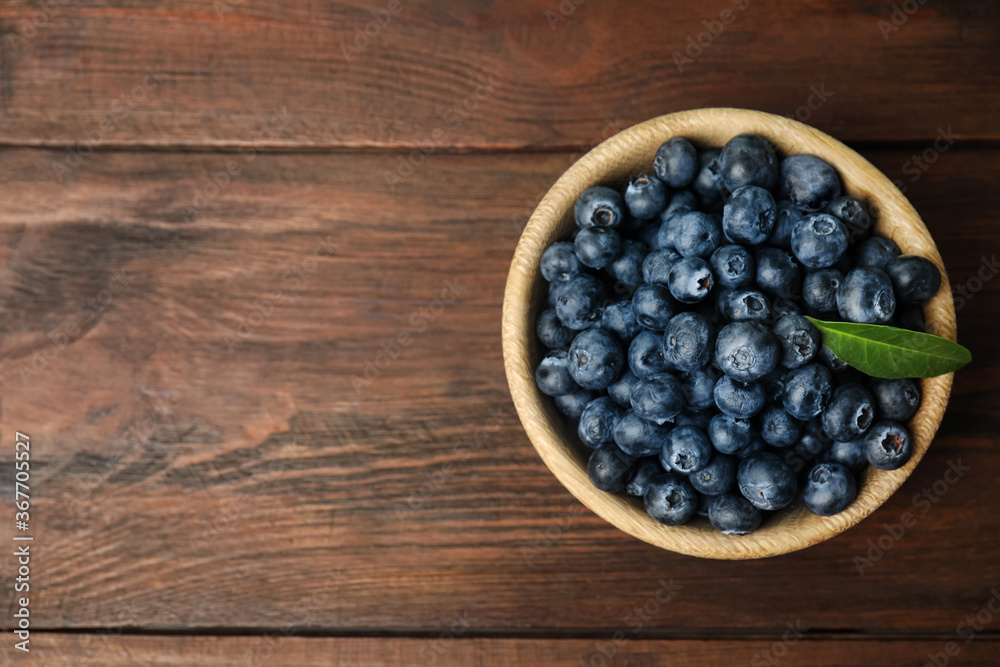 Tasty ripe blueberries in bowl on wooden table, top view. Space for text Tasty ripe blueberries in bowl on wooden table, top view. Space for text