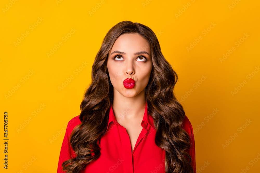 Photo of attractive funny curly lady shine glossy pomade look up empty space interested send air kisses formalwear red office shirt isolated bright yellow color background