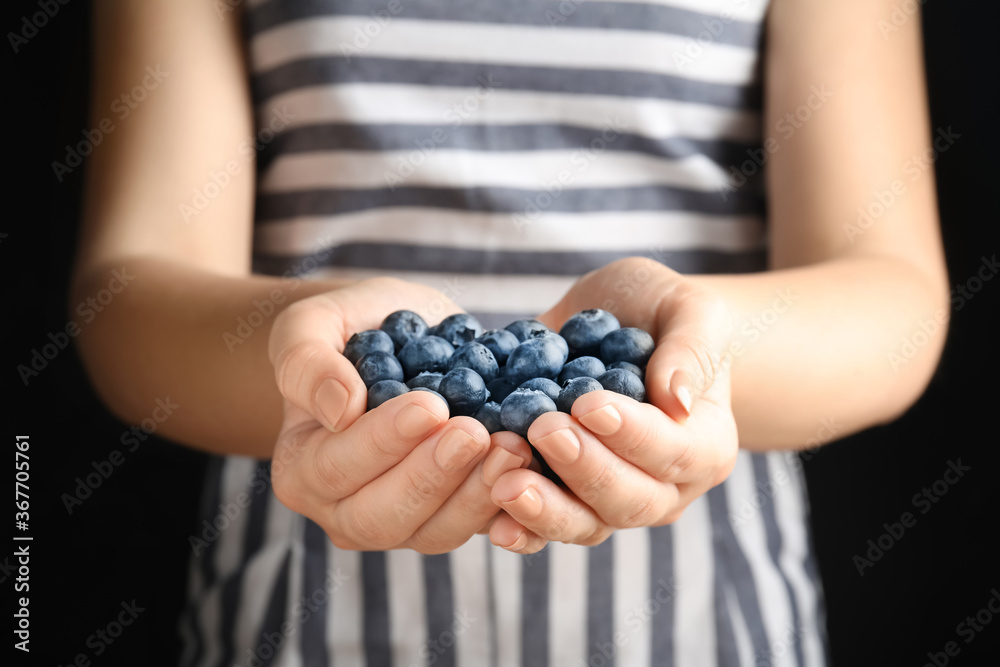 Woman holding juicy fresh blueberries on black background, closeup Woman holding juicy fresh blueberries on black background, closeup