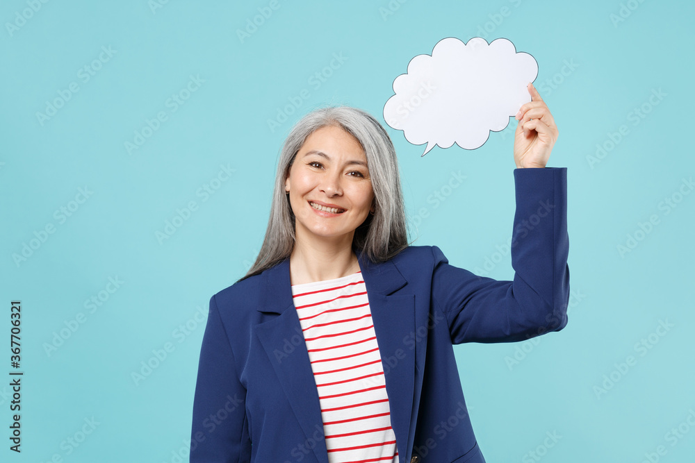 Smiling gray-haired business woman in blue suit posing isolated on pastel blue background. Achievement career wealth business concept. Mock up copy space. Hold empty blank Say cloud, speech bubble. Smiling gray-haired business woman in blue suit posing isolated on pastel blue background. Achievement career wealth business concept. Mock up copy space. Hold empty blank Say cloud, speech bubble.