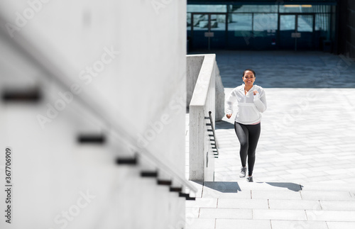 fitness, sport and healthy lifestyle concept - happy smiling young african american woman running upstairs outdoors