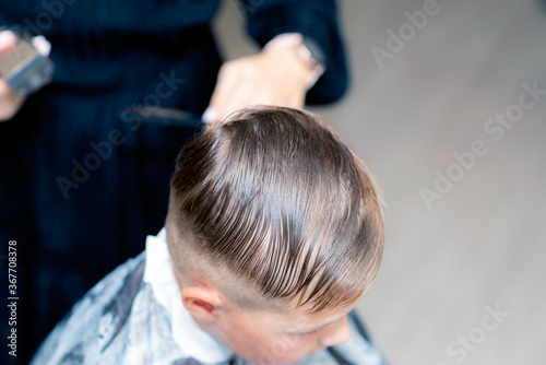 Close up american pretty school boy trendy haircut at bright modern barbershop.