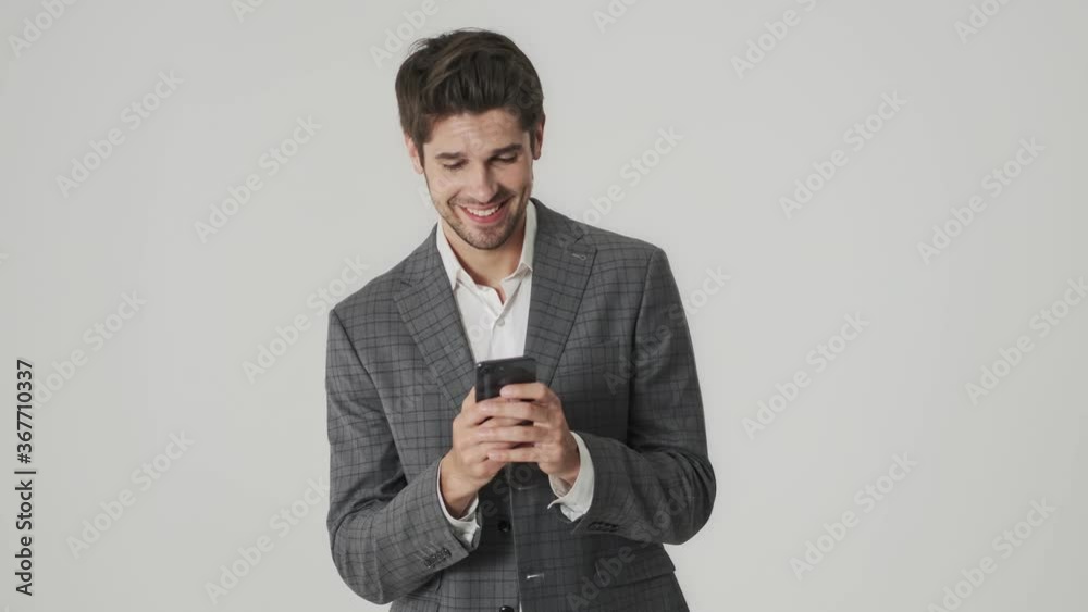 Young happy laughing business man isolated over white wall background while using mobile phone Young happy laughing business man isolated over white wall background while using mobile phone