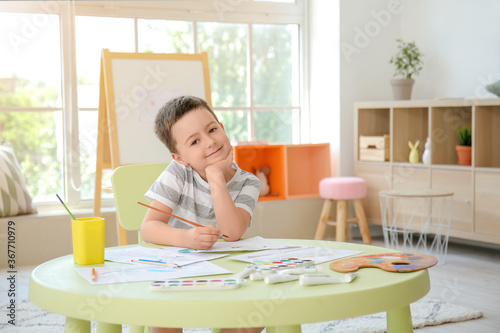 Happy young boy painting an...