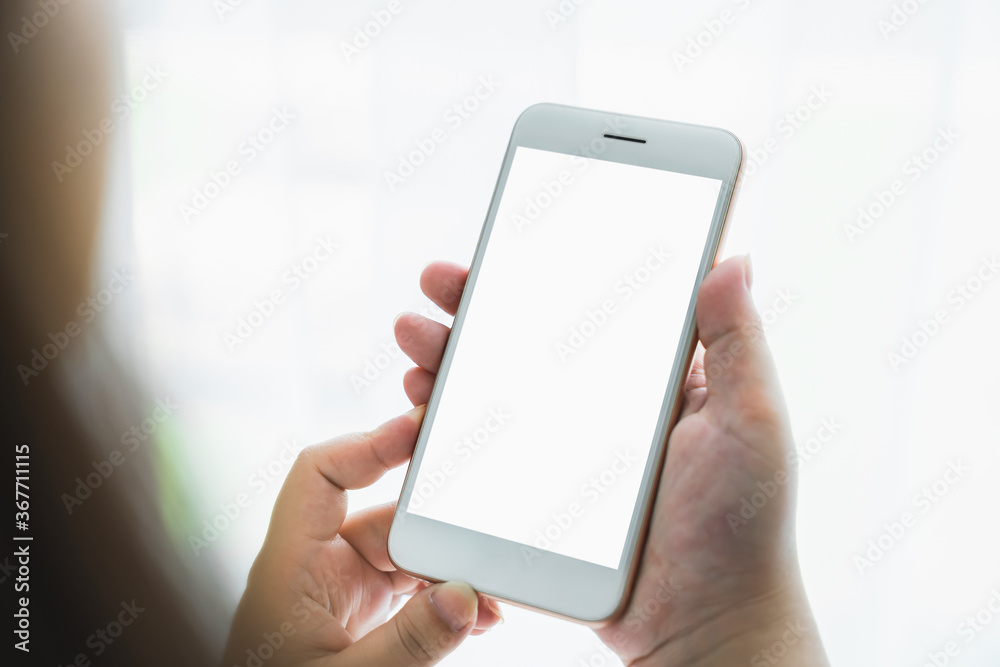 Woman hand holding smartphone and touching blank screen. Mockup of advertisement.