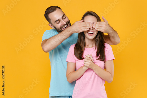 Cheerful surprised young couple friends guy girl in blue pink t-shirts posing isolated on yellow background studio portrait. People lifestyle concept. Mock up copy space. Covering eyes with hands.