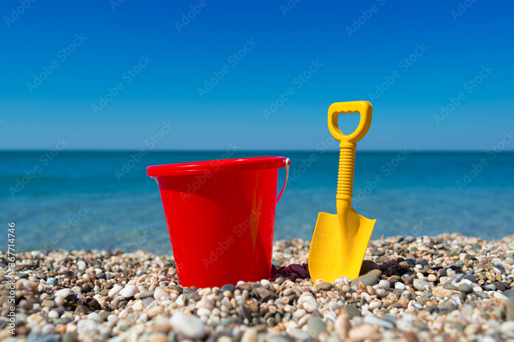 Toy bucket and spade on the beach stones Toy bucket and spade on the beach stones