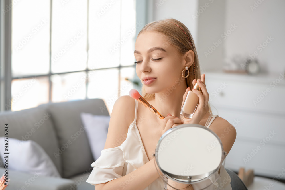 Beautiful young woman applying foundation at home Beautiful young woman applying foundation at home