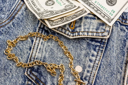 Gold chain and American dollars on a denim jacket. casual wear. Bijuteria. Jewelry. Fashionable accessories. Close-up photo
