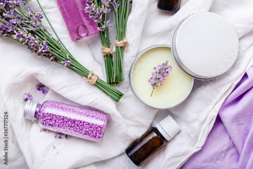 Set lavender skincare cosmetics products. Natural spa beauty products fresh lavender flowers on fabric. Lavender essential oil bottle body butter massage oil cream soap bath beads gel liquid. Flat lay