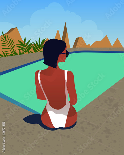 Beautiful girl sits by the pool and enjoys the summer sun and relaxation