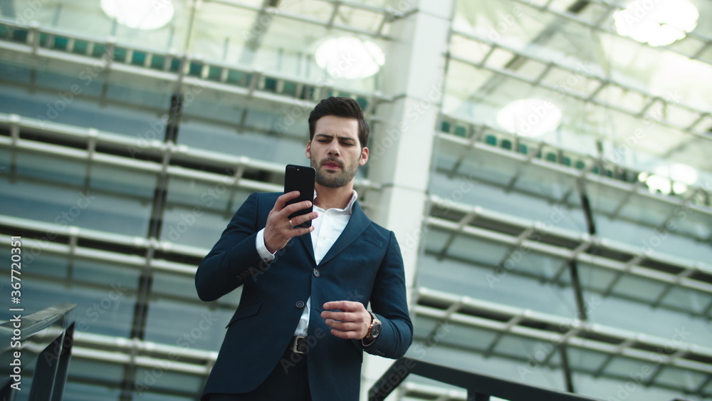 Closeup businessman picking up phone. Man standing in luxury suit near stadium