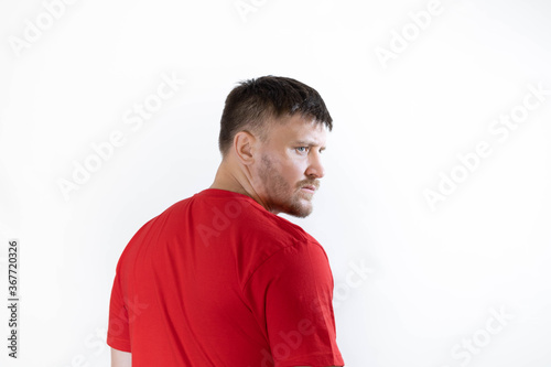 A man with a beard in a red T-shirt stands with his back to us.