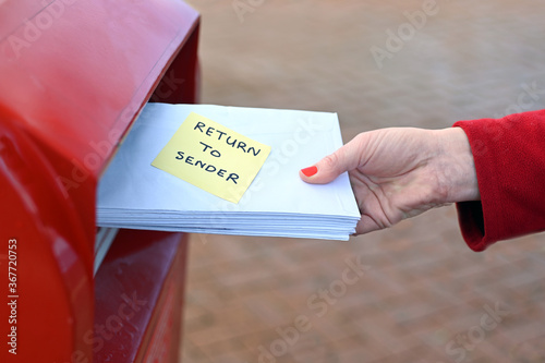Konstfotografi Woman sending return to sander letters in envelope in red mail box