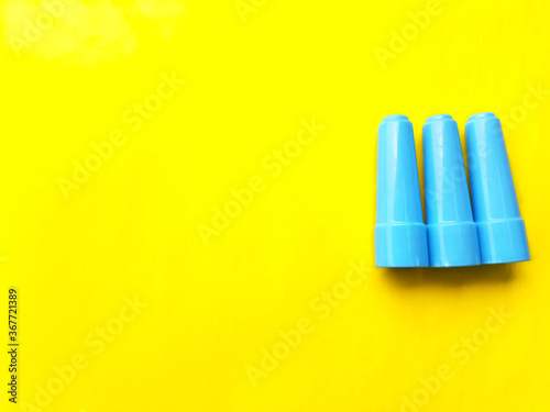 Synthetic plastic toy sticks pattern and copy space for text  blue colored small cap sticks placed on yellow background.