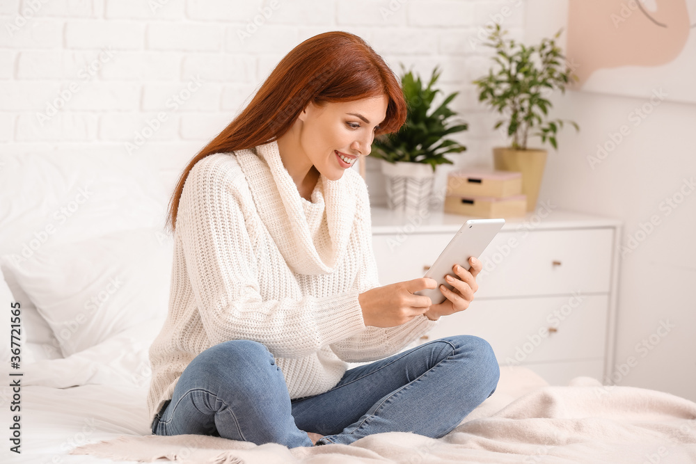 Beautiful redhead woman using tablet computer at home Beautiful redhead woman using tablet computer at home