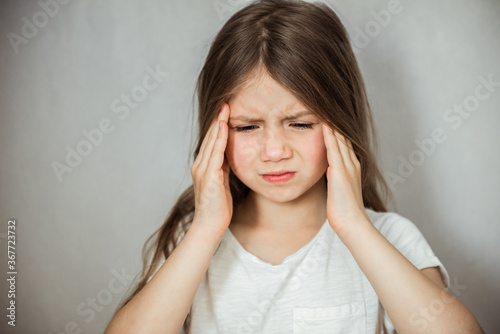Fotografía Cute girl suffering from headache on gray background