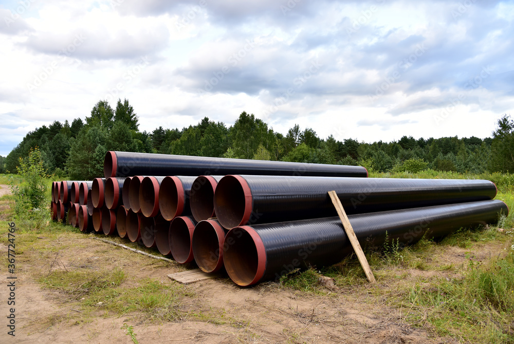 Crude oil and Natural gas pipeline construction work in forest area. Petrochemical Pipe on top of wooden supports. Installation and Construction the Pipeline for transport gas to LNG plant Crude oil and Natural gas pipeline construction work in forest area. Petrochemical Pipe on top of wooden supports. Installation and Construction the Pipeline for transport gas to LNG plant