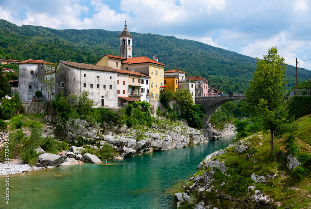 Obraz premium Kanal ob Soči Soča Slowenien Brücke Dorf Ort Fluss Tal Smaragdfluss Panorama Kirche Felsen Ufer Sommer Baden Natur ursprünglich grün türkis kristallklar Idyll Landschaft