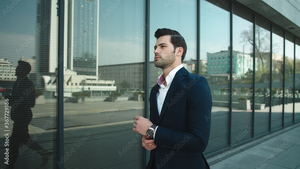 Portrait man checking time on watch. Businessman walking in suit at street Portrait man checking time on watch. Businessman walking in suit at street