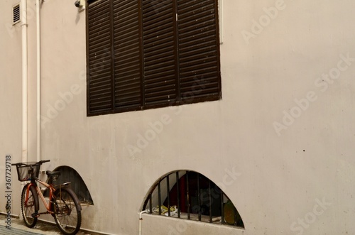 Bicycle leaning against a wall cream coloured wall with square and semi circle shaped windows. photo