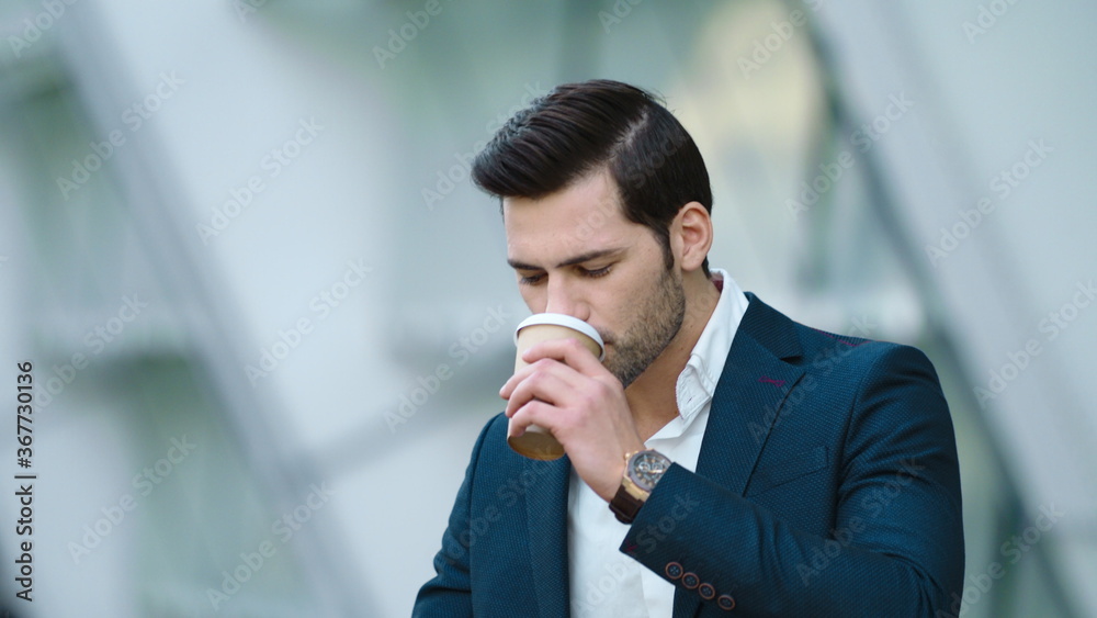 Portrait man standing with coffee and phone. Man drinking take away coffee Portrait man standing with coffee and phone. Man drinking take away coffee