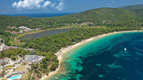 Aerial drone photo of beautiful popular organised sandy bay, turquoise beach and natural preserve lake with pine trees of Koukounaries, Skiathos island, Sporades, Greece