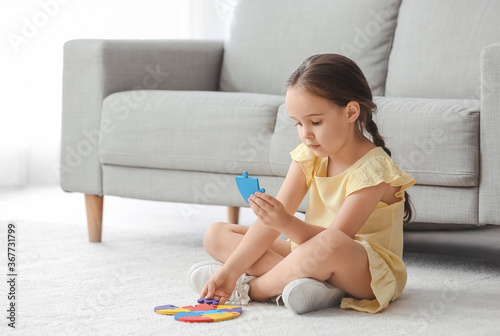 Little girl with autistic disorder doing puzzle at home