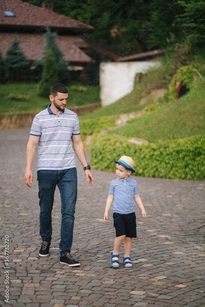 Fototapeta premium Father walking with sun outdoors. Happy family. Boy in straw hat