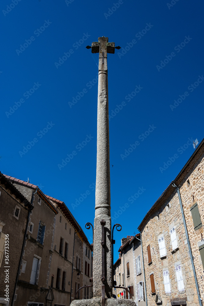 Stone cross and Flowers ,in the medieval town  of Malzieu , lozere France .a stage in the way of compostelle a long distance walk .