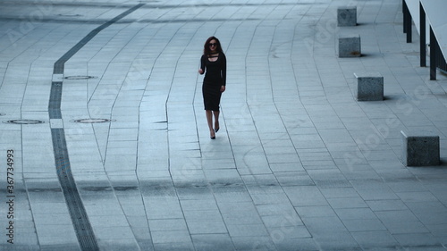 Woman walking in slow motion at sidewalk. Woman taking off sunglasses at street