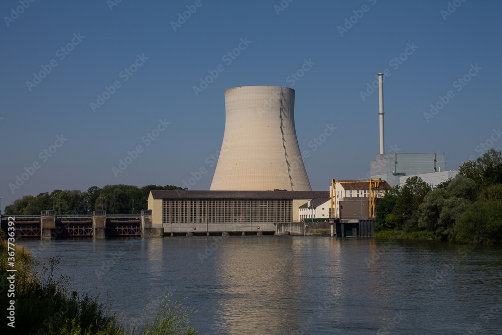 The cooling tower of a nuclear power plant is reflected in a river. In front of it is a hydropower plant. The cooling tower of a nuclear power plant is reflected in a river. In front of it is a hydropower plant.