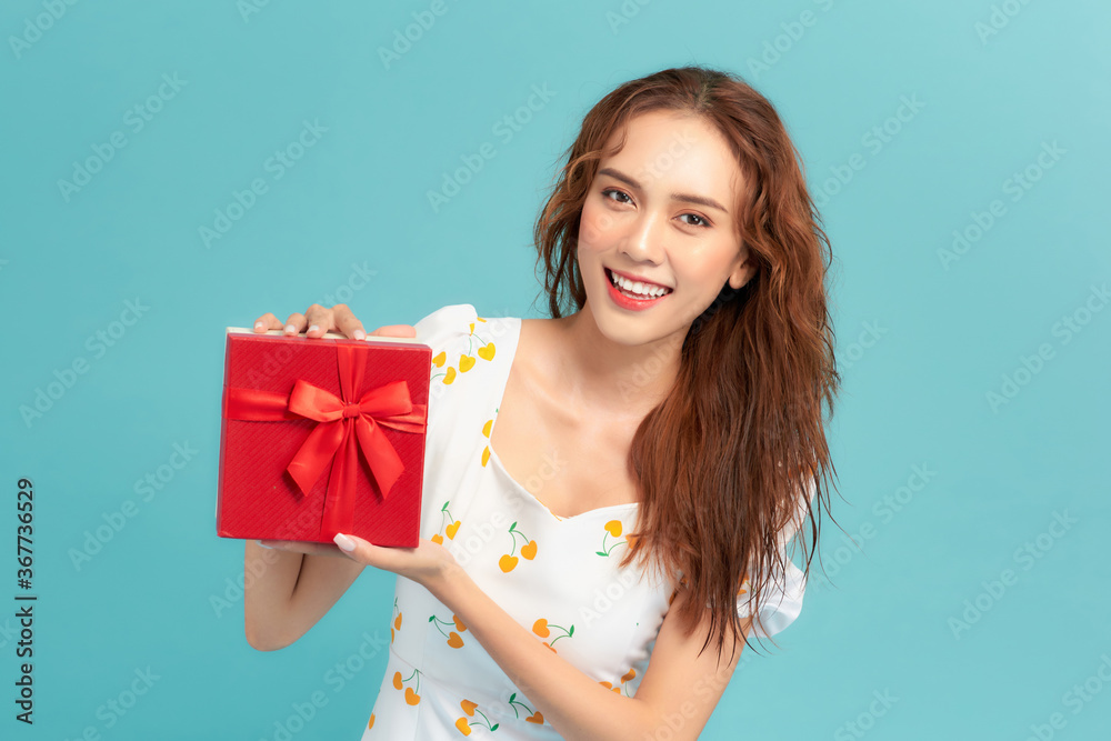 Happy smiling girl in dress holding present box and over blue background Happy smiling girl in dress holding present box and over blue background